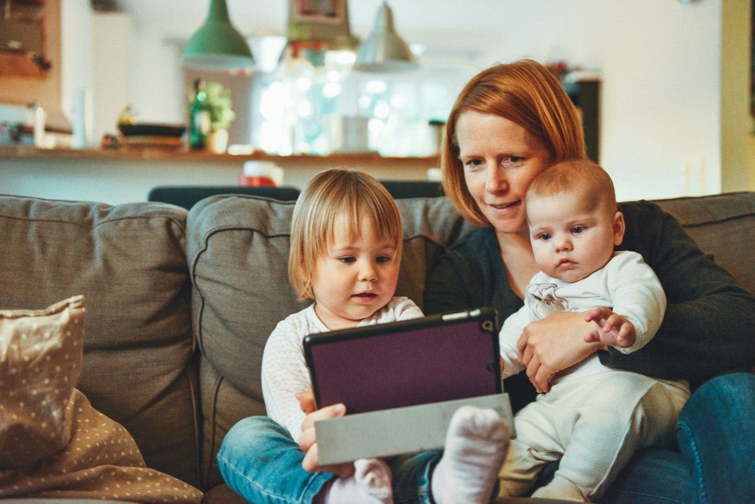 A parent and two young children at home